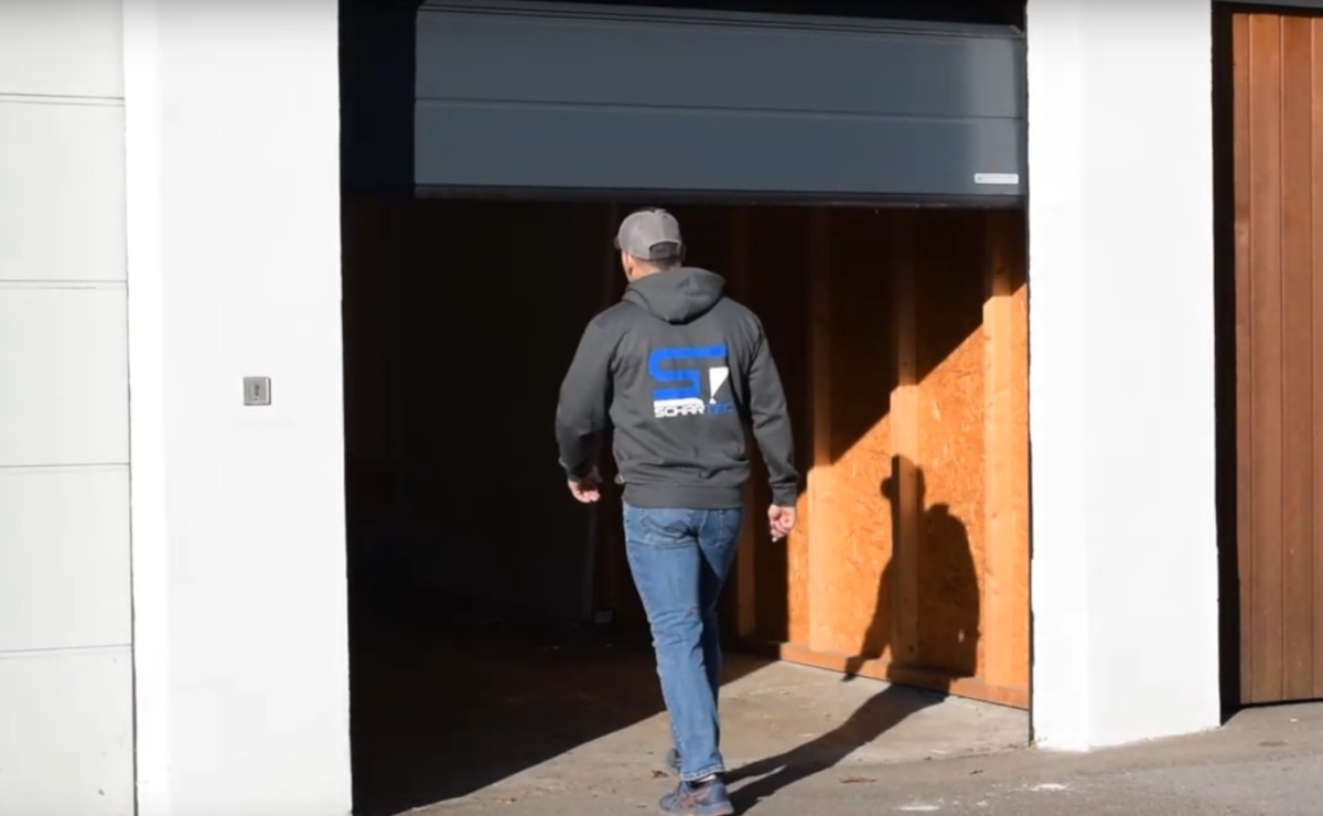 garage-betreten-bei-stromausfall Man betritt Garage bei teilweise geöffnetem Garagentor